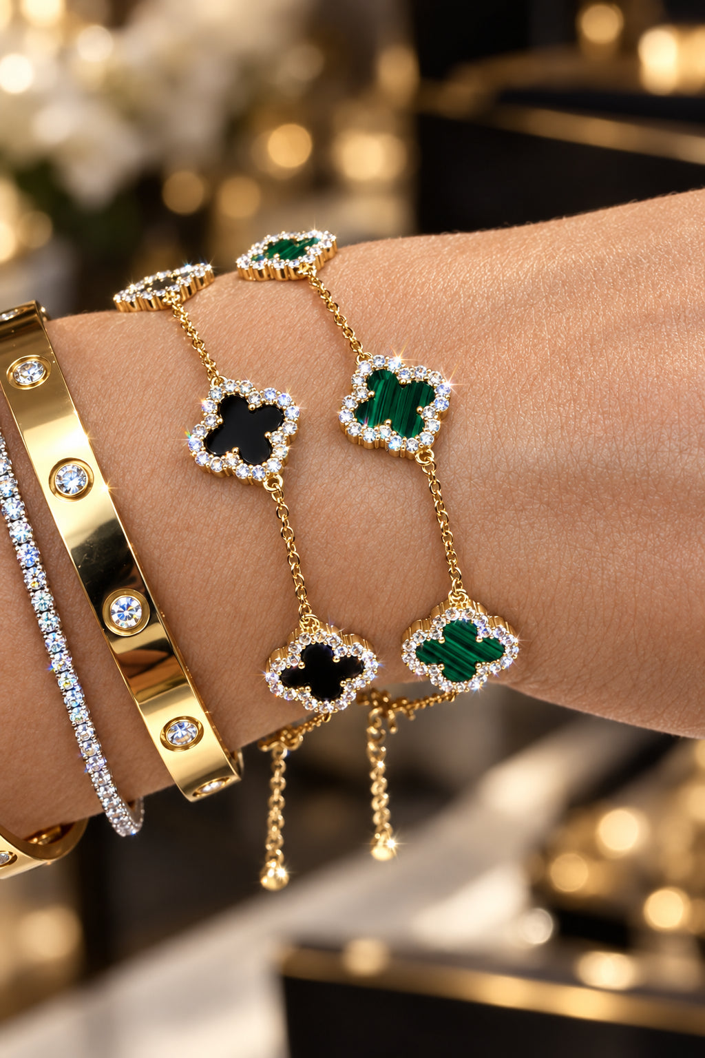 Gold bracelet with clover-shaped charms on a wrist against a neutral background