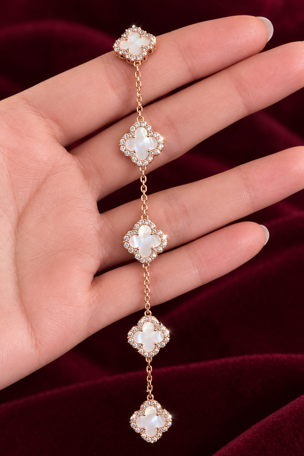 Delicate gold chain with clover pendants held in a hand against a dark background