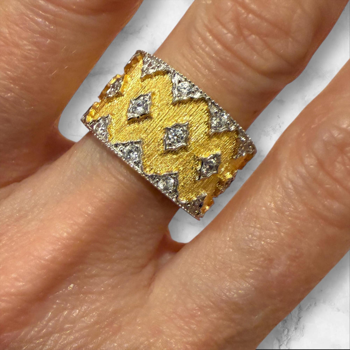 Buccellati 18k yellow and white gold band ring on a finger featuring an iconic hand-etched rigato texture, brilliant-cut diamond lozenge motifs, and distinctive scalloped edges
