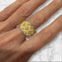 Gold and diamond ring in the Buccellati style worn on a finger over a marble surface featuring yellow gold with rigato engraving, scalloped white gold borders, and star-shaped diamond accents