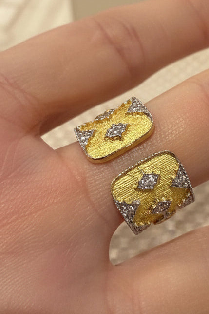 Contemporary yellow gold and diamond bypass ring worn on a finger featuring two textured rectangular plates with pavé-set diamond accents and raised star-shaped motifs