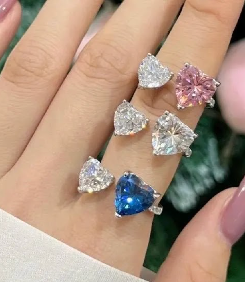 Heart-shaped gemstone rings on a hand with a blurred background