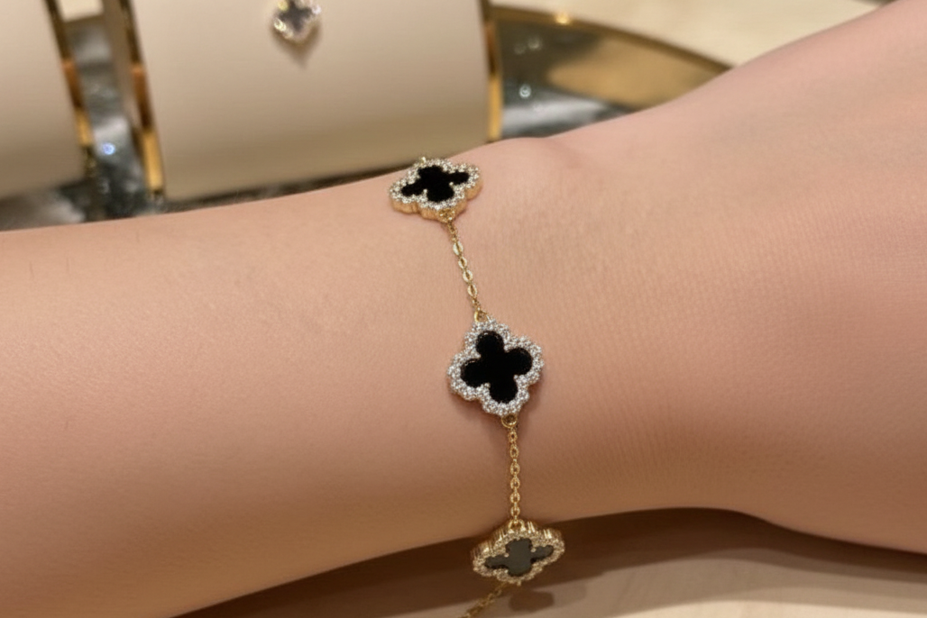 Gold bracelet with black clover designs on a wrist Ali & Eve Jewels