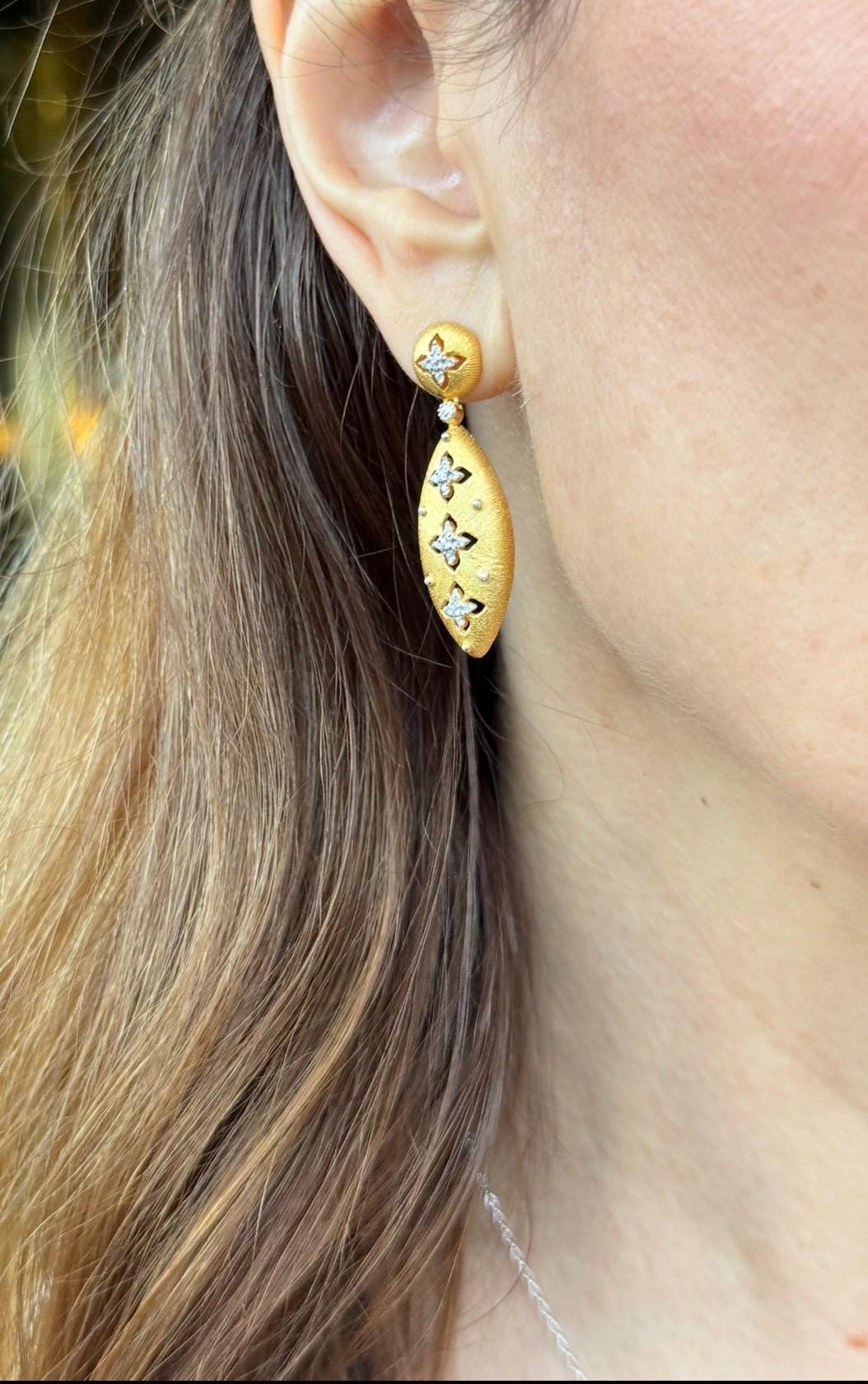 Close-up of a person wearing gold earrings with star designs  - Ali & Eve Jewels