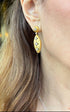 Close-up of a person wearing gold earrings with star designs  - Ali & Eve Jewels