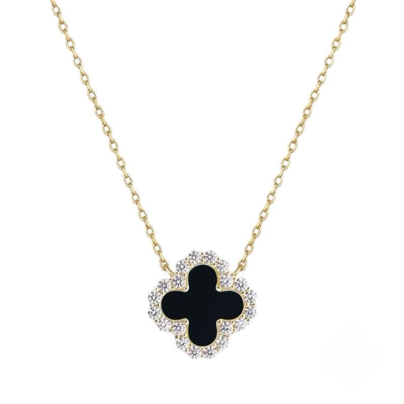 Jewelry by Van Cleef & Arpels featuring the iconic Alhambra clover motif as a black onyx pendant bordered by brilliant-cut diamonds on a yellow gold chain against a white background