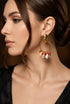 Gold earring with red and white stones worn by a person