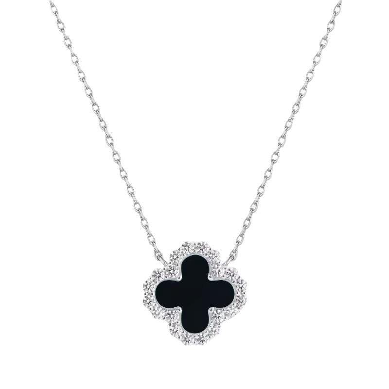 White gold necklace by Van Cleef & Arpels featuring the iconic Alhambra clover motif in a white studio setting with a polished black onyx center and a shimmering border of brilliant-cut diamonds