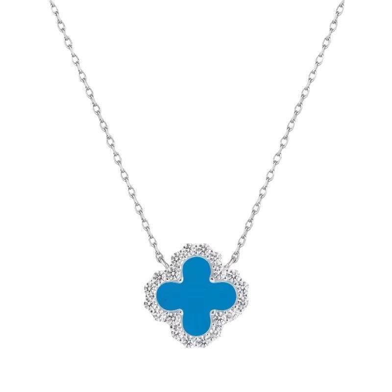 Van Cleef & Arpels white gold necklace featuring the iconic blue turquoise Alhambra motif pendant surrounded by a halo of sparkling pavé diamonds and a delicate silver chain on a white background