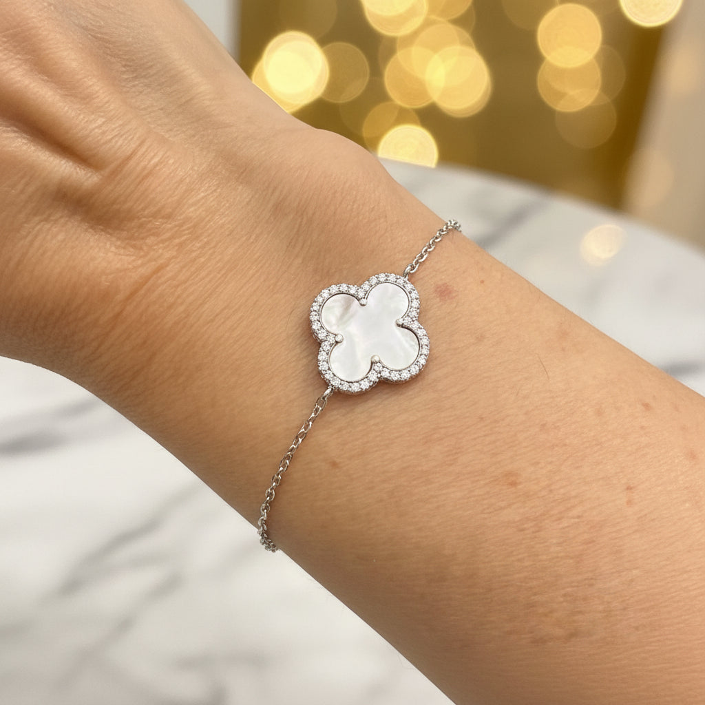 Silver bracelet with a clover-shaped mother of pearl gemstone on a wrist 