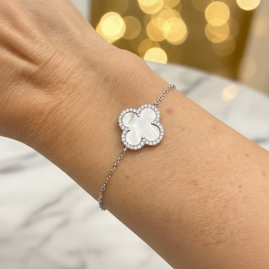 Silver bracelet with a clover-shaped mother of pearl gemstone on a wrist 