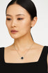 Studio photograph of a Van Cleef & Arpels necklace worn by an Asian woman in a studio setting, featuring the iconic Alhambra clover pendant with a black onyx center and diamond-studded border on a delicate white gold chain